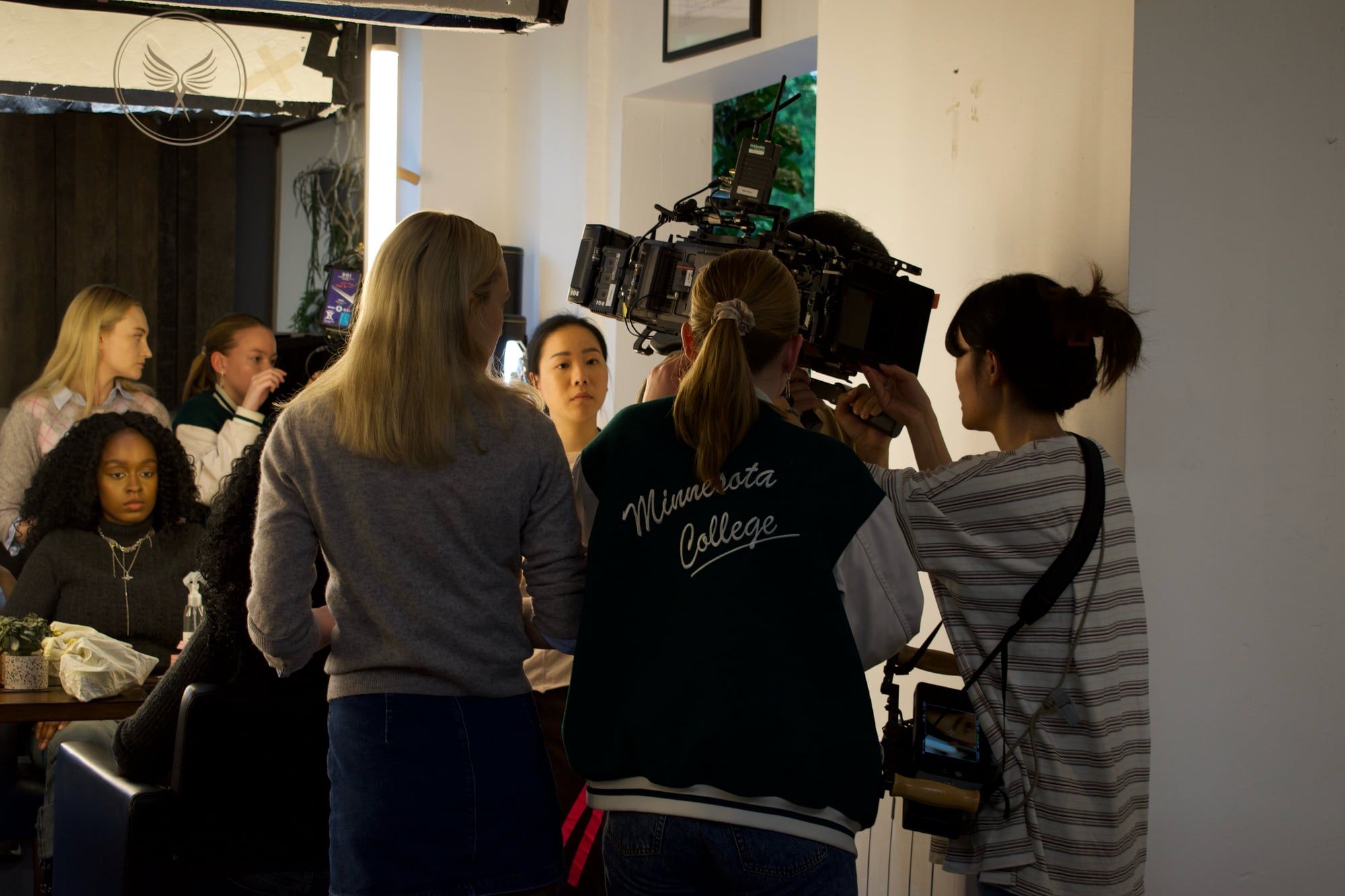 A crowded set, with the camera operator carrying the rig on his shoulder and actors and crew packed round the reception desk. (opens a larger view)